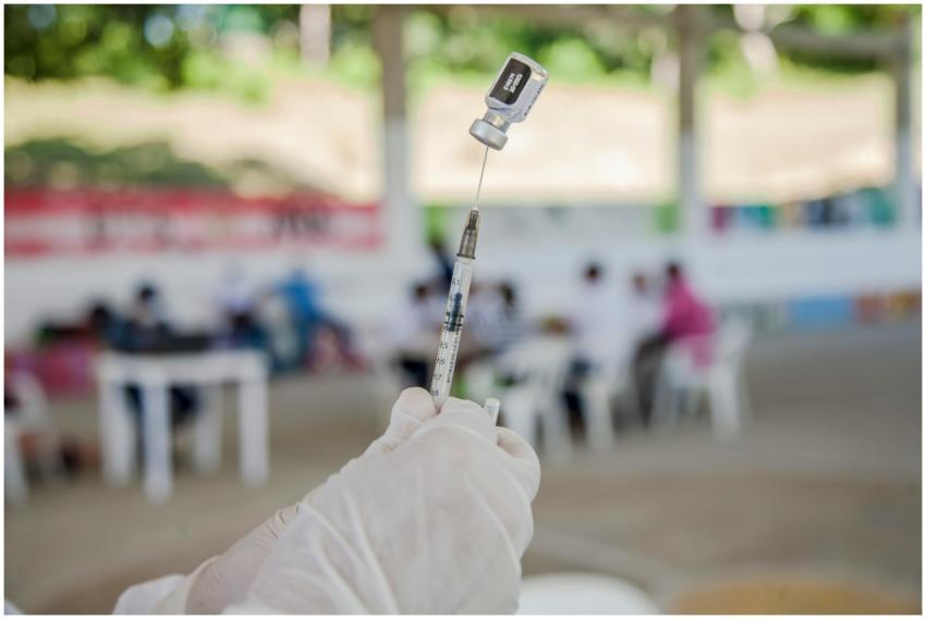 A medical professional prepares a syringe for vacc