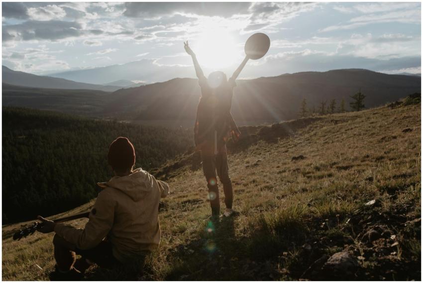 Two people enjoying a musical moment on a hillside