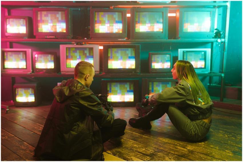 Two people sitting in a retro setting surrounded b