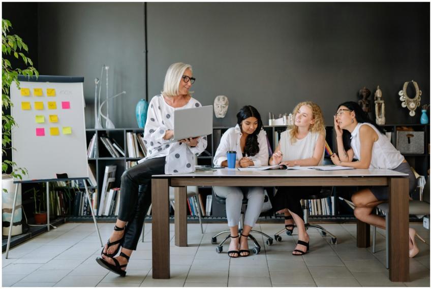 Four women collaborate in a modern office space, f