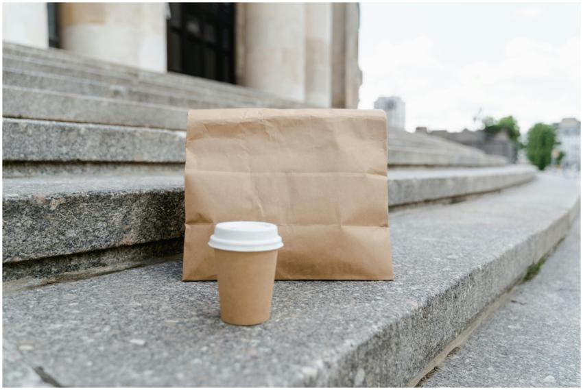 A paper bag with a coffee cup on stone steps in an