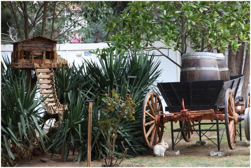 Vintage cart and wooden treehouse in a garden sett