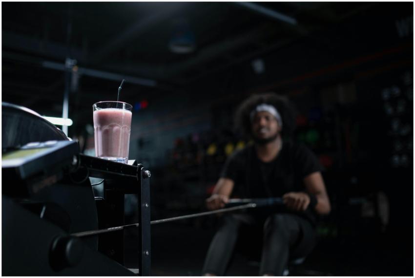Glass of strawberry smoothie on exercise machine,
