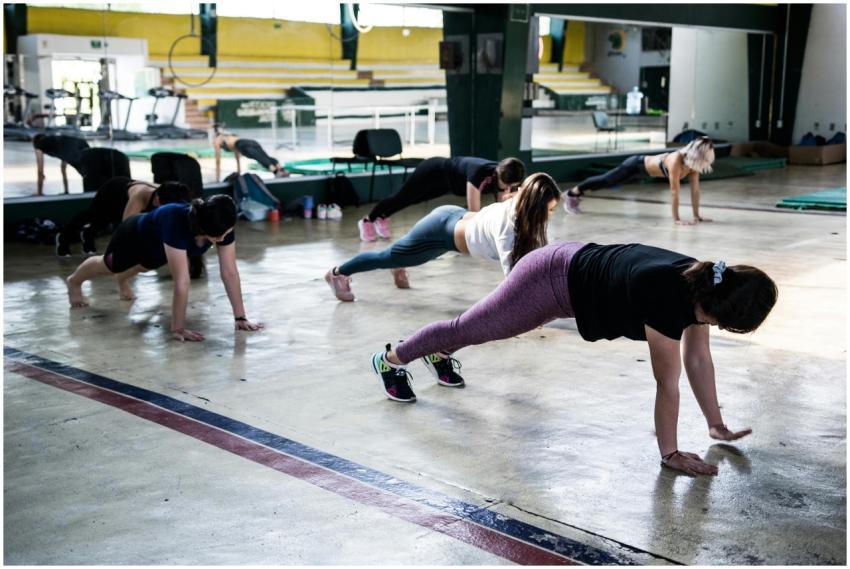 Group of women doing push-ups in a gym reflecting