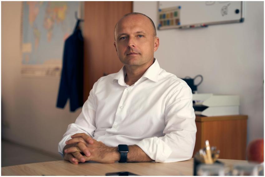 A confident adult man in a white shirt sitting in