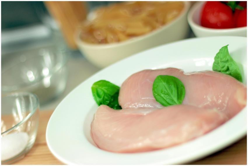 Close-up of raw chicken breasts on a plate with ba
