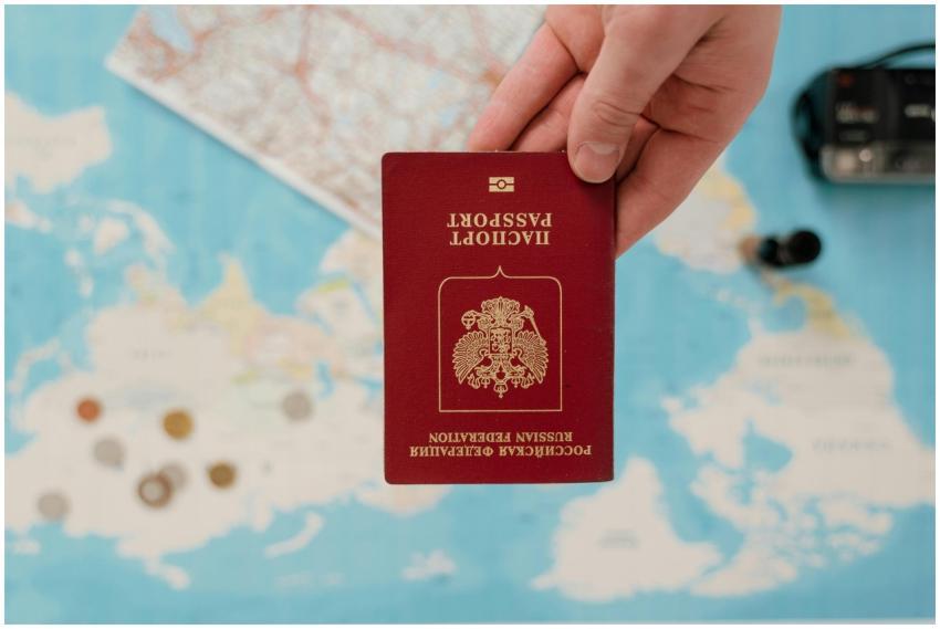 A hand holding a Russian passport over a map, sugg