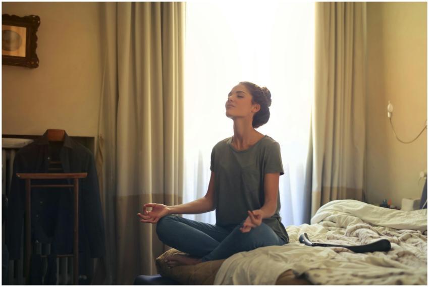 Adult woman practicing meditation on her bed surro