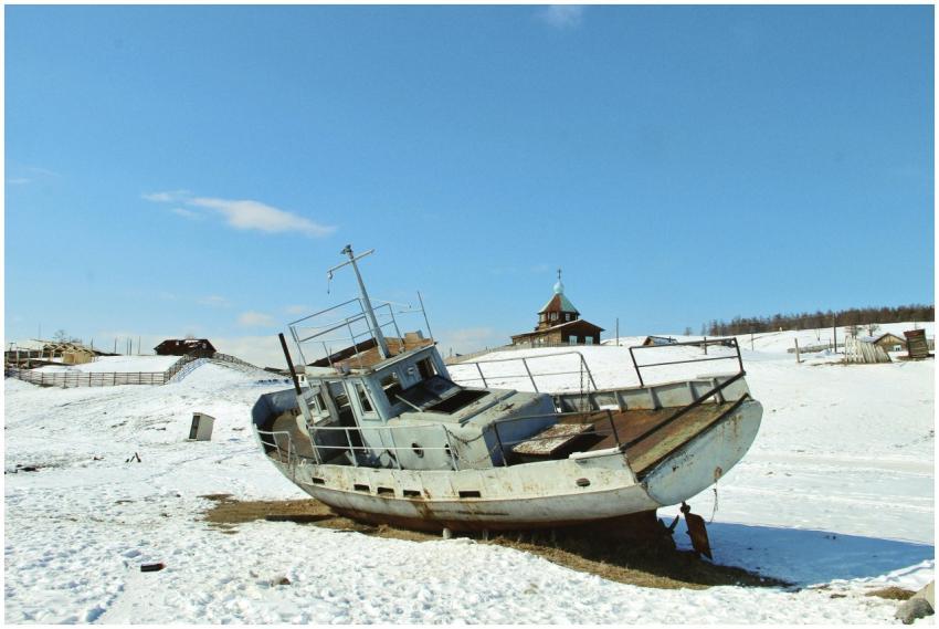 An old boat rests abandoned in a snowy landscape,