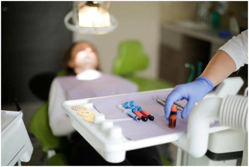 Crop dentist in blue rubber medical gloves curing