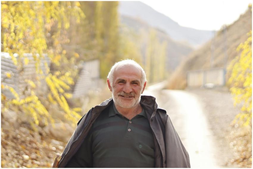 Senior man smiling while standing on a sunlit path