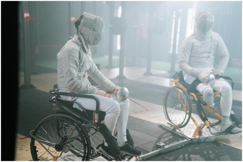 Two male wheelchair fencers practicing in a gym, f