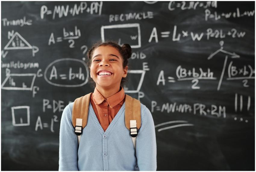 Smiling girl with backpack in a classroom, standin