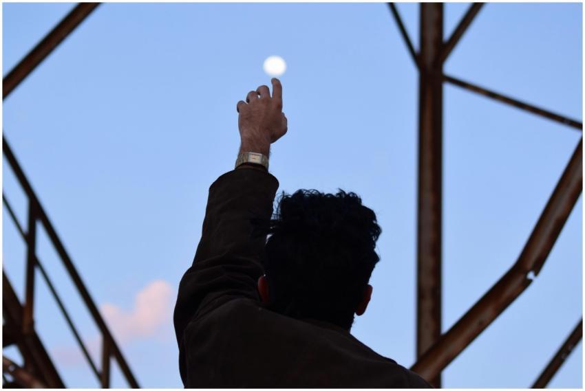 A man silhouetted against the morning sky reaches