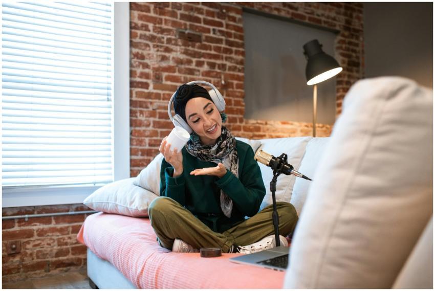 Woman podcasting at home, wearing headphones and s