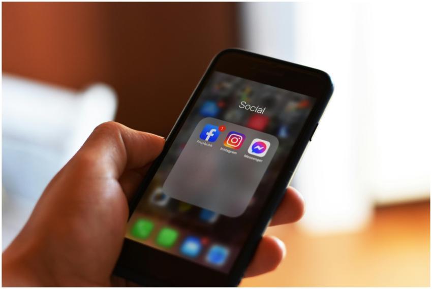 Close-up of hand holding smartphone showing social