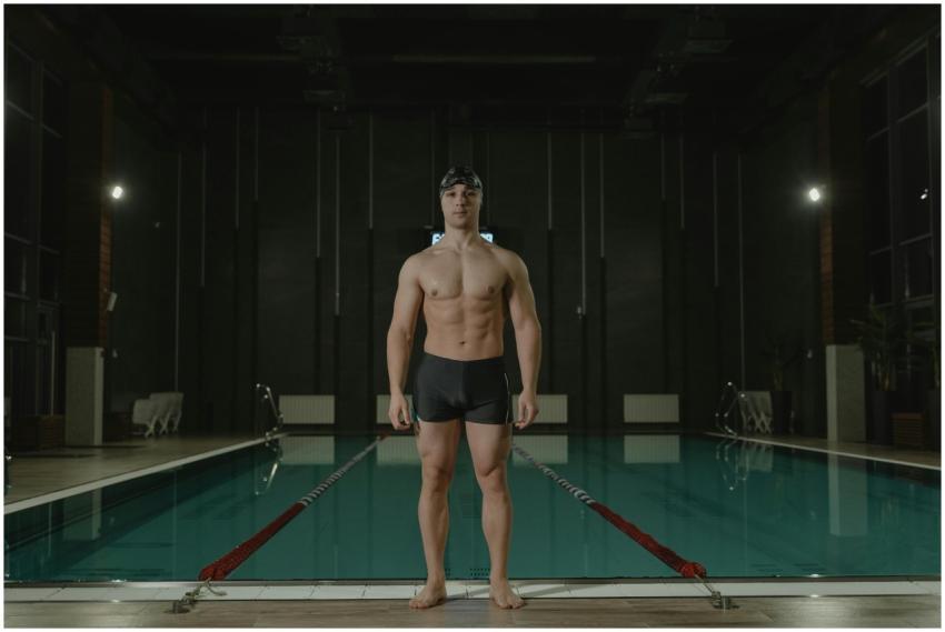 Athletic male swimmer standing confidently poolsid
