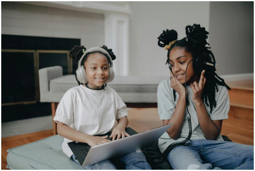 Two smiling girls with dreadlocks enjoying music o
