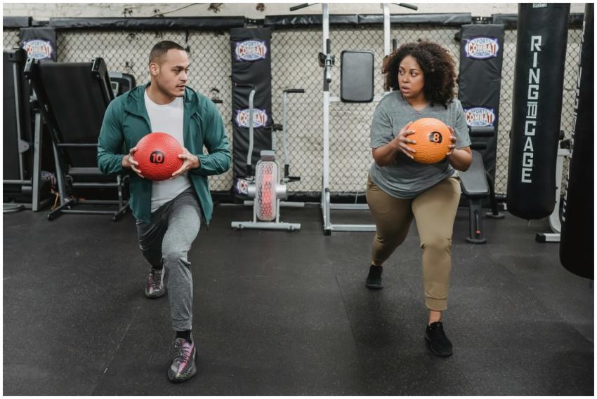 Two individuals performing lunges with medicine ba