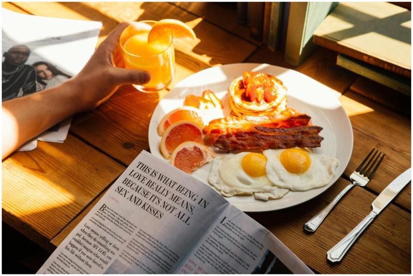 Sunlit breakfast with bacon, eggs, pancakes, and o