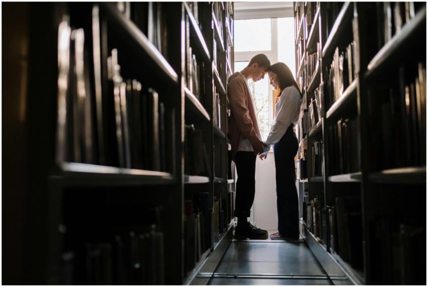 A young couple embracing in a library, symbolizing