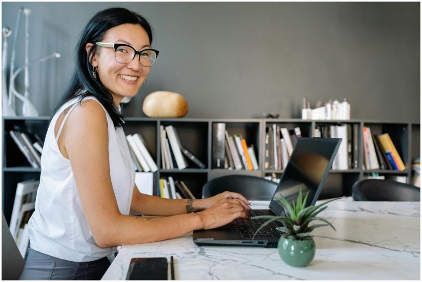 Cheerful businesswoman using laptop at a desk in a