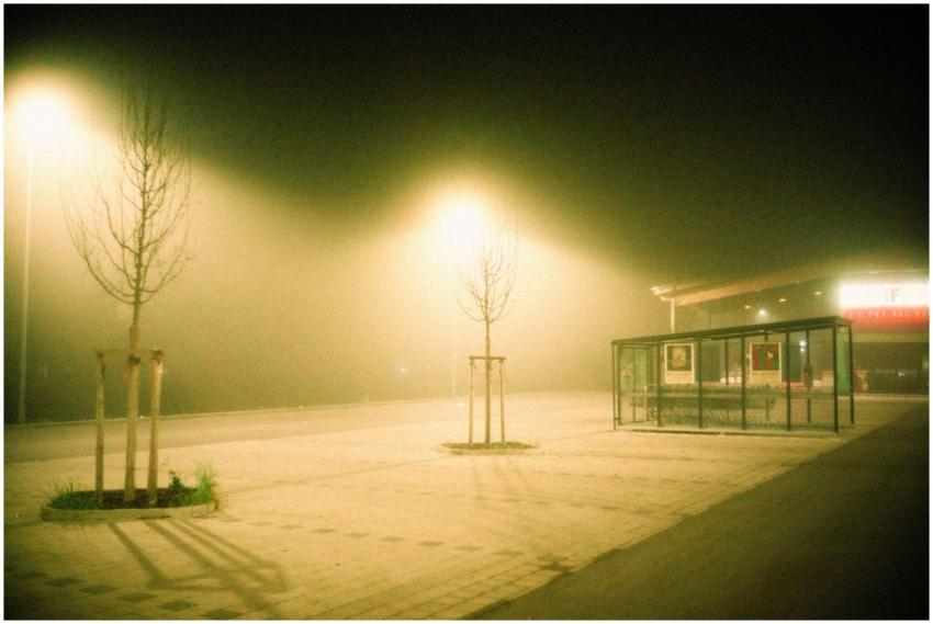 A foggy, deserted street at night illuminated by g