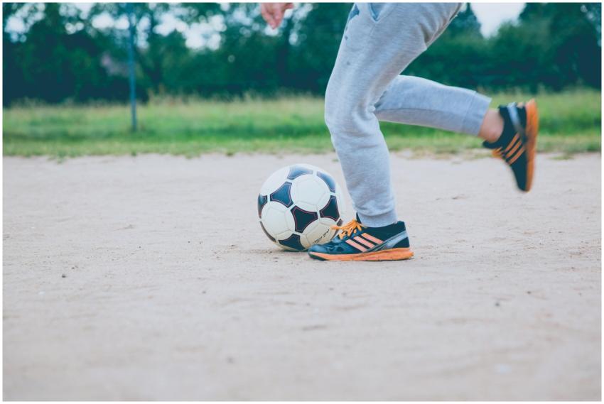 Young player practicing soccer on a sandy outdoor
