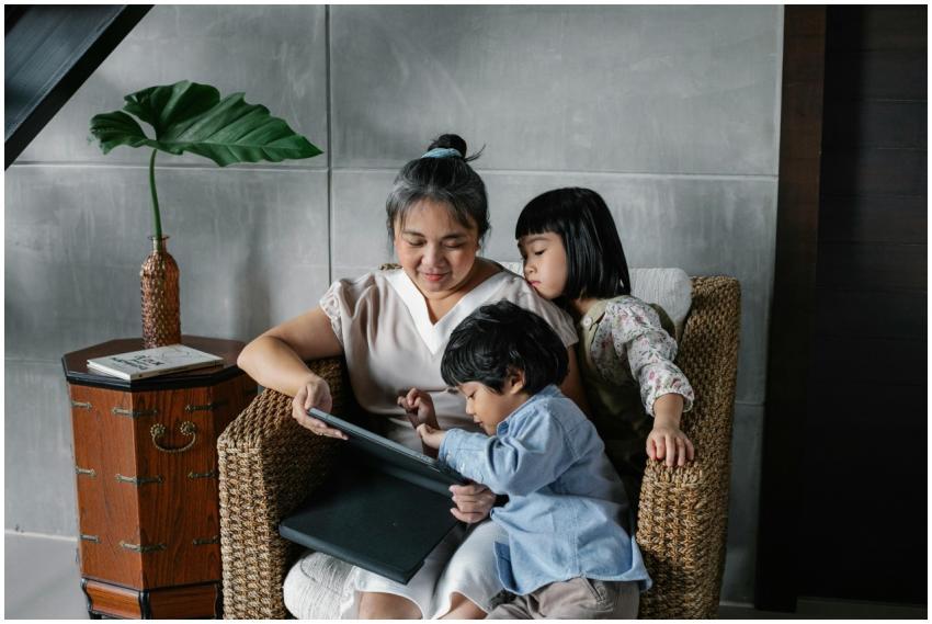 Calm Asian woman sitting with kids and using table