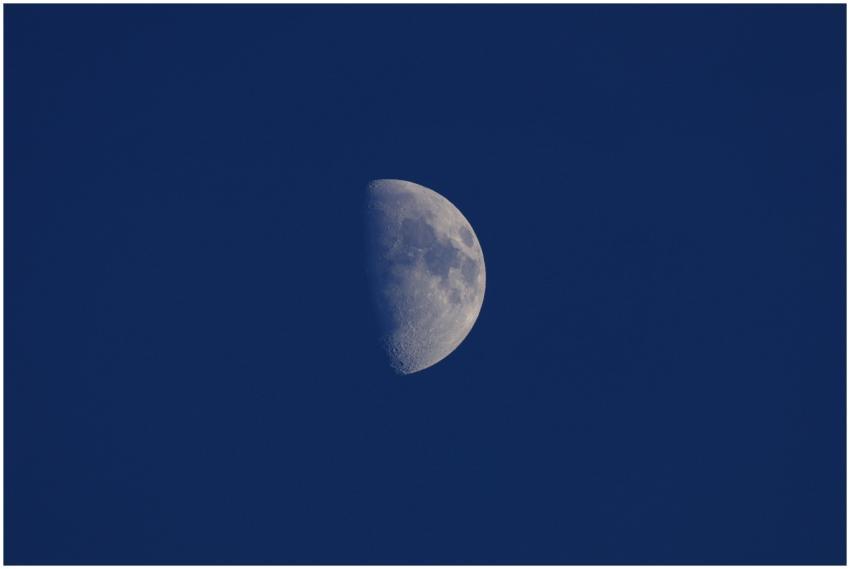 A stunning half moon shining brightly against a cl