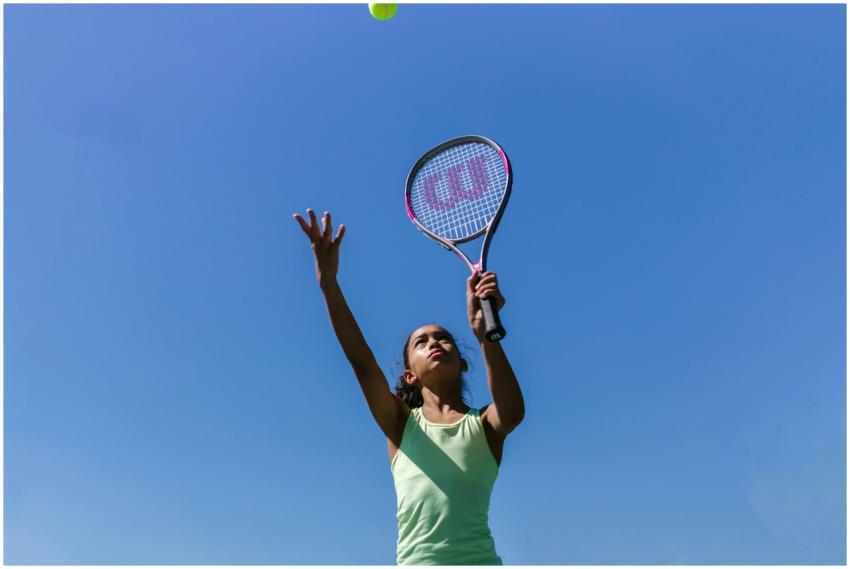 Teen girl playing tennis outdoors, focusing on ser