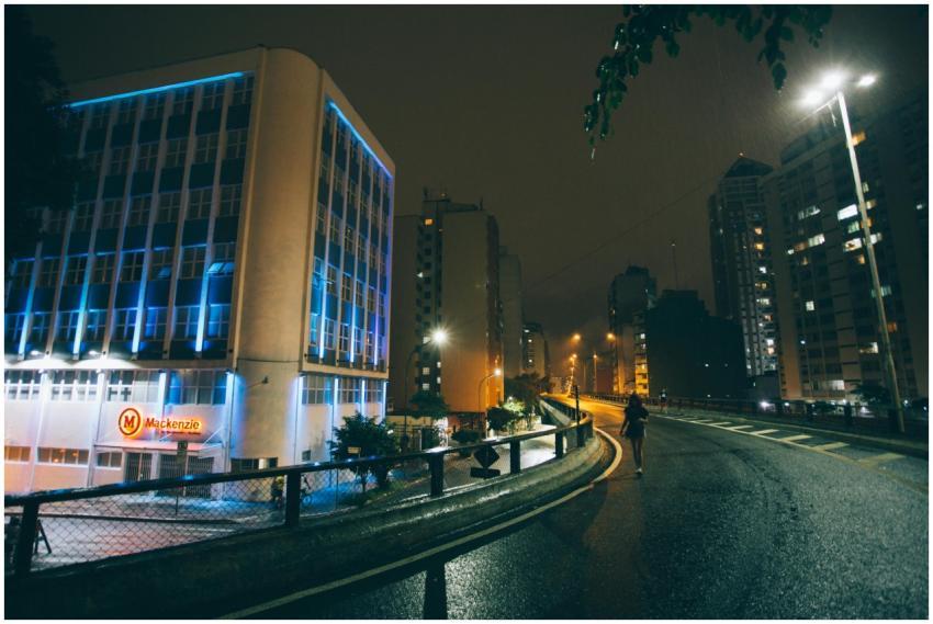 A solitary person walks on a wet city street at ni