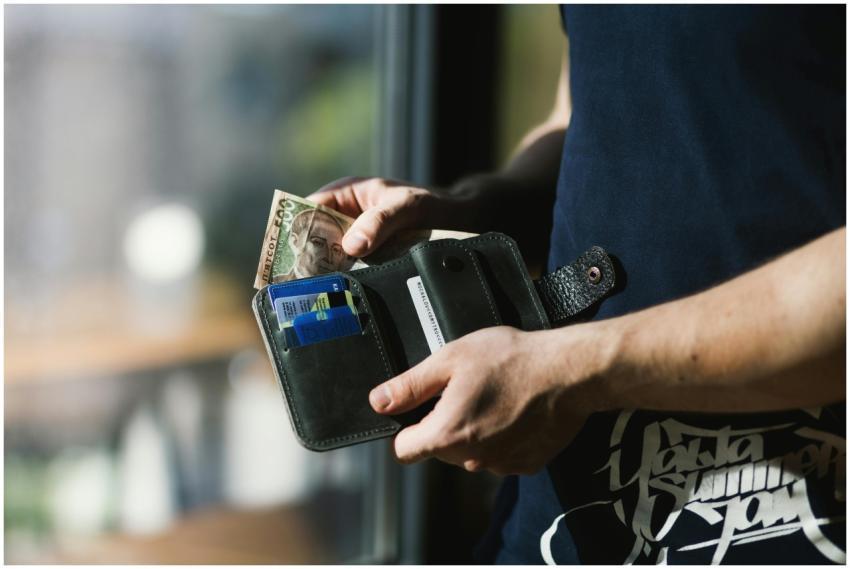 Close-up of a man holding a wallet with cash and c