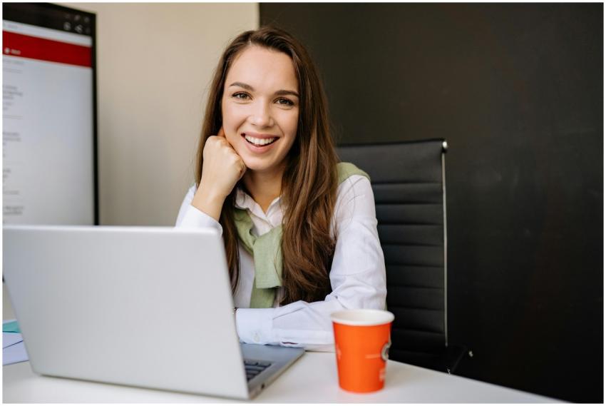 Businesswoman sitting at desk in office, smiling a