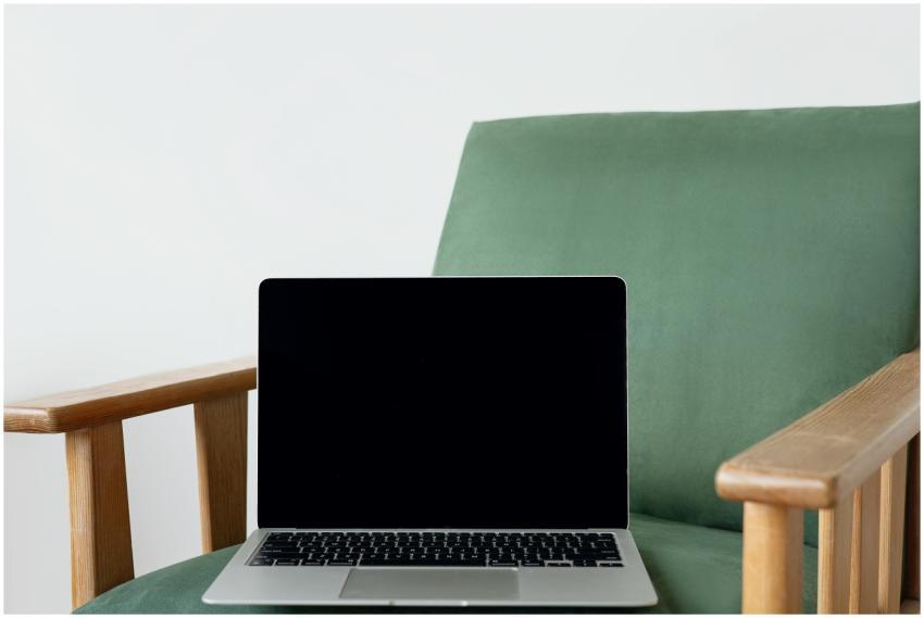 A sleek laptop sits on a stylish green chair, perf