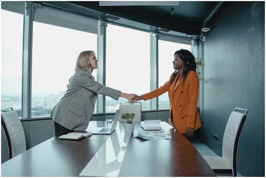 Two businesswomen shaking hands in a modern office