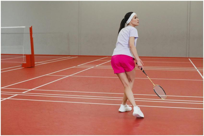 Woman playing badminton indoors with focus and agi