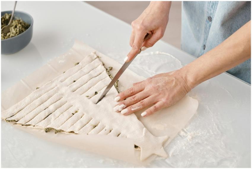 Close-up of hands slicing pastry dough in creative
