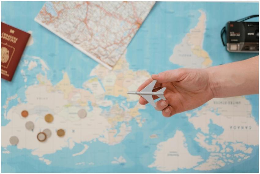 Hand holding a toy airplane over a world map, surr