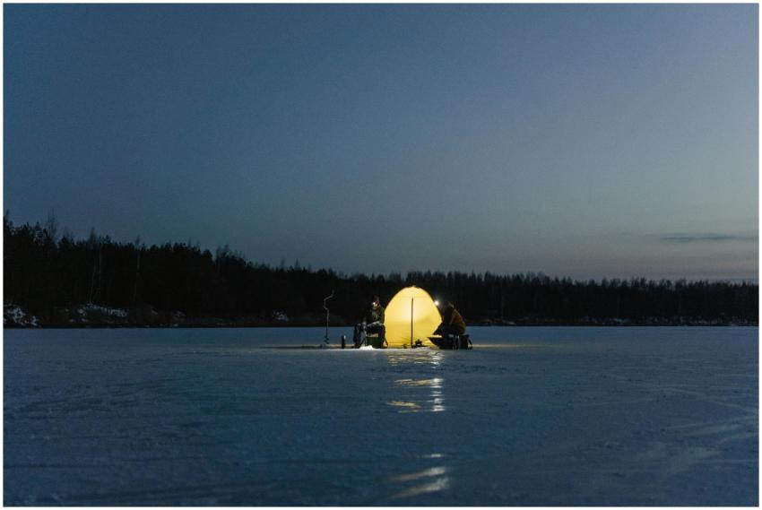 Two people camping on a frozen lake at night with