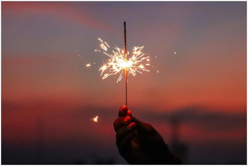 Close-up of a hand holding a sparkler against a co