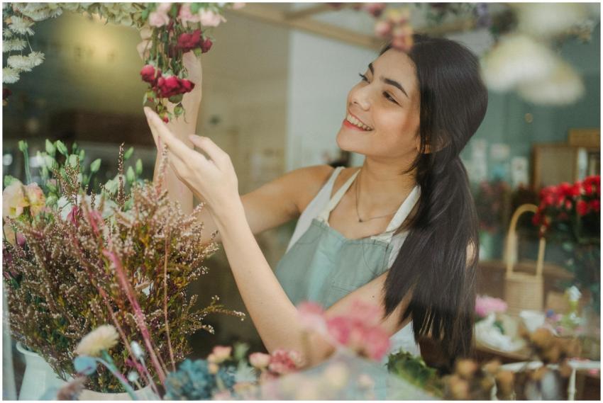 Young smiling dark haired female florist in apron