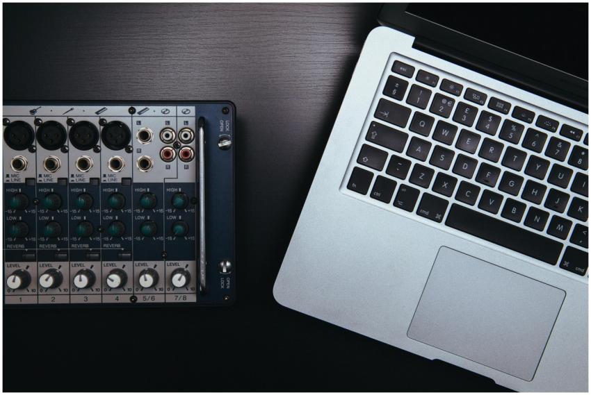 Close-up of audio mixer and laptop, essential for
