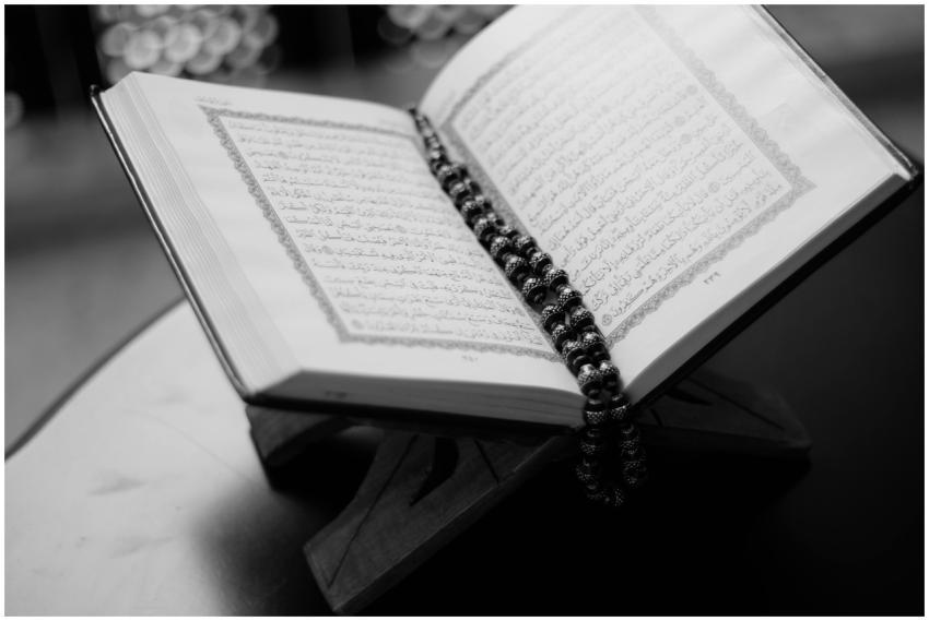 A black and white close-up of an open Quran on a w