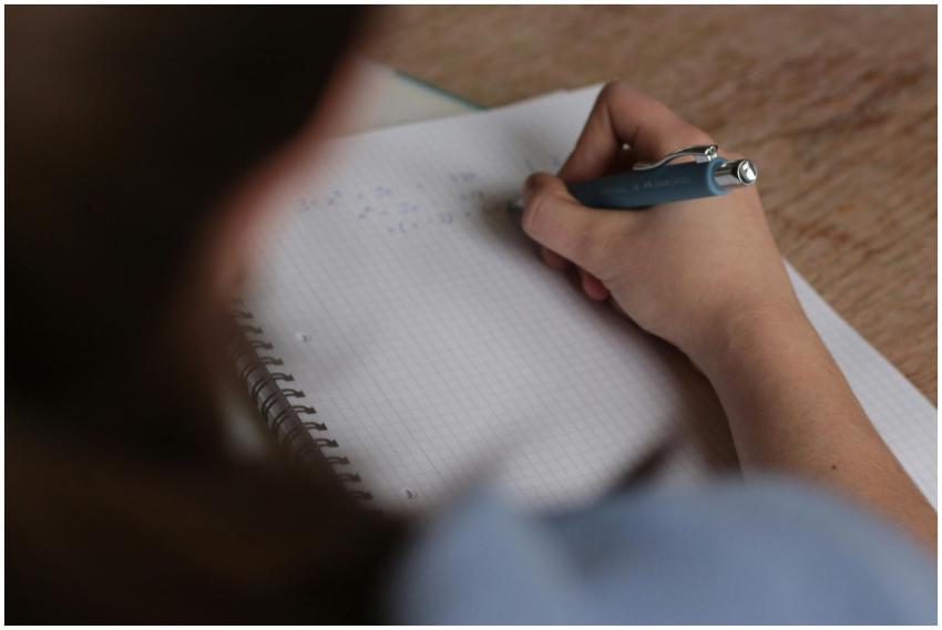 A student writes mathematical notes in a notebook