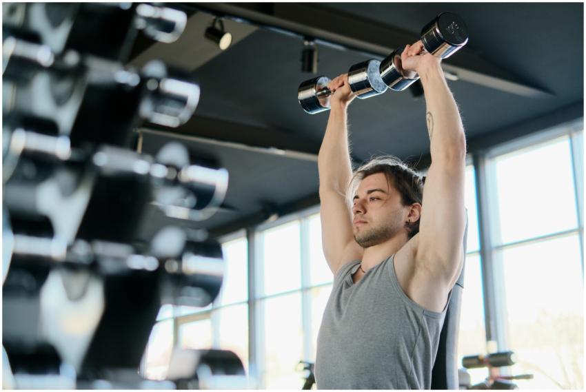 Man performing shoulder press with dumbbells in a