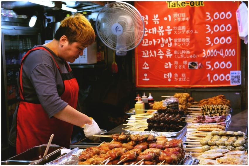 A street food vendor prepares Korean skewers at an