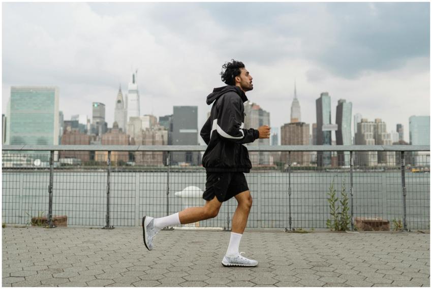 Adult man jogging along a waterfront with the New