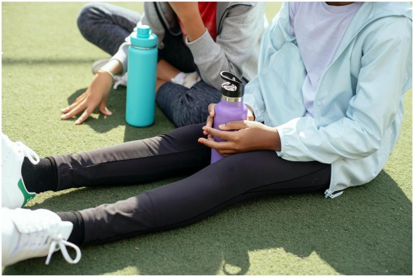 Crop schoolgirls with plastic water bottles sittin