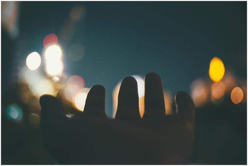 A hand reaching towards colorful bokeh lights at n